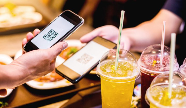 Hand using smart phone to scan QR code on tag with blurry food, dessert and customers in restaurant to accepted generate digital pay without money. Qr code payment concept.