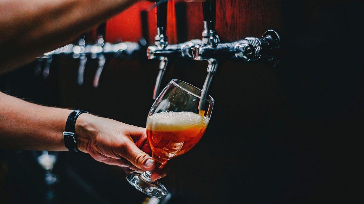 bartender hand at beer tap pouring a draught beer in glass serving in a restaurant or pub